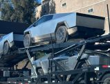 Tesla Cybertrucks on a delivery truck, signifying their distribution to businesses.