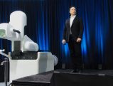 Elon Musk standing next to futuristic white device on stage