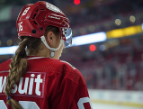 Female ice hockey player wearing red jersey with "Lawsuit" on the back
